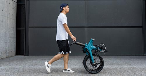 A man pushes a folded Fiido X e-bike away